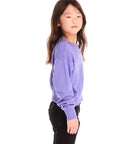 Side view of girl wearing Chaser’s purple Snow Day Athletic Club long sleeve with text and graphics on a white background