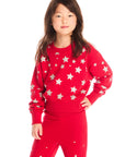 Girl wearing Chaser’s Danni Rouge Pullover with star patterns and matching Tara Leggings on a white background