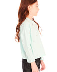 Side view of young girl wearing Chaser’s Ciao Allover Stars light green pullover with light grey star patterns and dark jeans on a white background