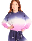 Girl wearing Chaser’s Glitter Stars Ombre Tie Dye Long Sleeve with colorful star patterns and matching pants on a white background