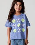 Front view of a girl wearing the Chaser Happy Bows Tee on a neutral background