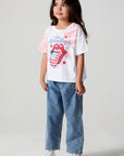 A full body side angle view of a girl wearing the Chaser The Rolling Stones Americana Stones Tee and jeans on a neutral background