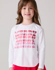 Model wearing Chaser's Merry Girls Long Sleeve Tee in white with pink and red Merry lettering, front view