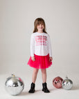 Model wearing Chaser's Merry Girls Long Sleeve Tee in white with holiday lettering, editorial view