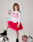 Model wearing Chaser's Merry Girls Long Sleeve Tee in white with holiday lettering, editorial view