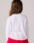 Model wearing Chaser's Merry Girls Long Sleeve Tee in white with pink and red Merry lettering, back view