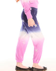 Side view of girl wearing Chaser’s Slim Ombre Tie Dye Pants with colorful glitter star patterns and matching long sleeve top on a white background