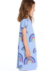 Side view of the Chaser Kids Allover Rainbows Short Sleeve Shirt Dress in Blue Hydrangea featuring colorful rainbow graphics on a white background