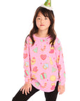 Girl wearing Chaser’s pink Tossed Candy Canes Long Sleeve with colorful candy cane designs and a Christmas tree hat on a white background