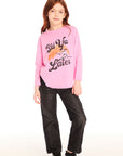 Full body view of girl wearing Chaser’s pink Ski Ya Later Long Sleeve with text and graphics and black jeans on a white background