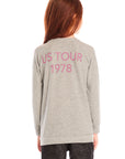 Back view of girl wearing Chaser’s gray The Rolling Stones Spiral Tongues Long Sleeve with “US TOUR 1978” text in pink on a white background