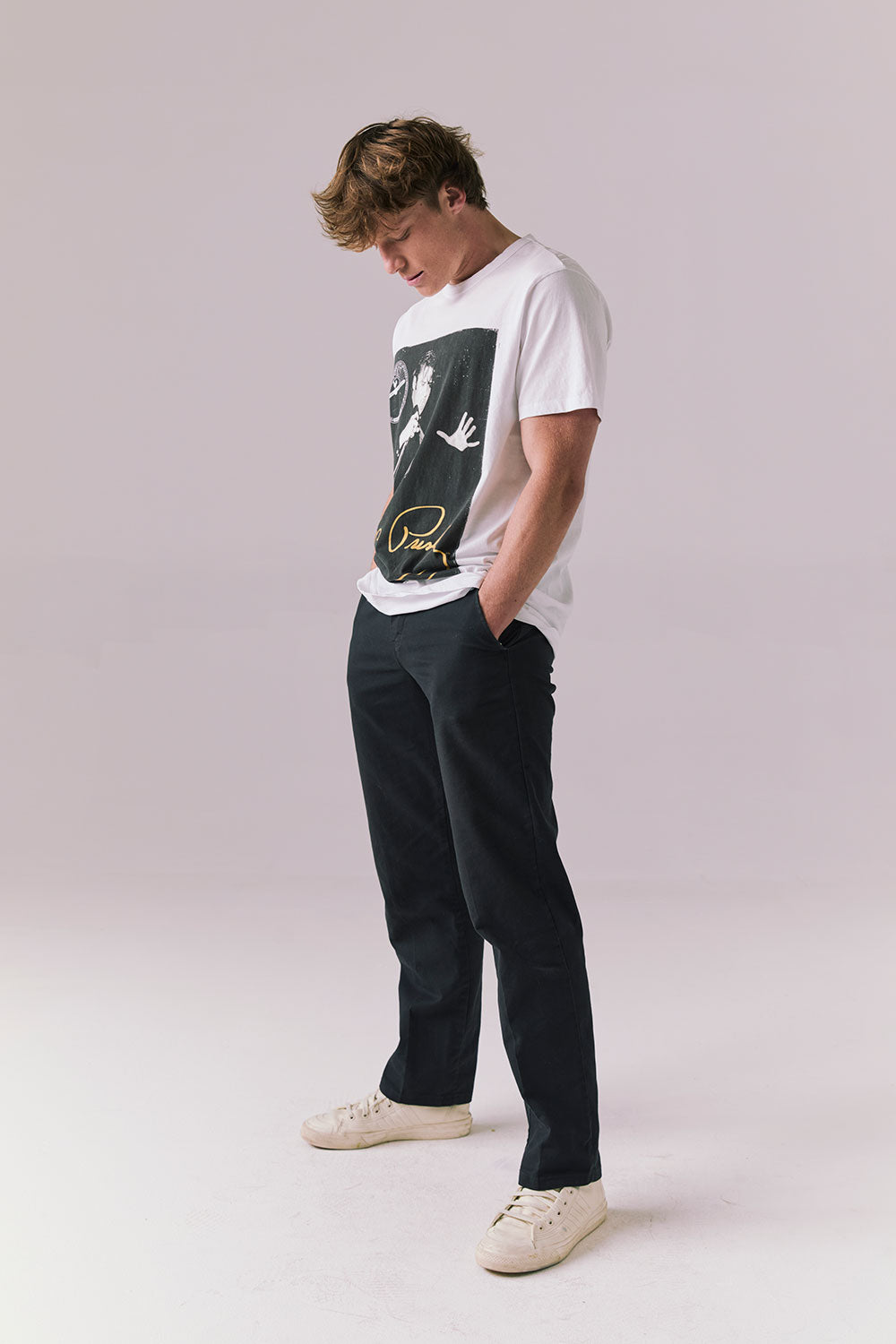 Side full body view of model in Elvis graphic tee in white.
