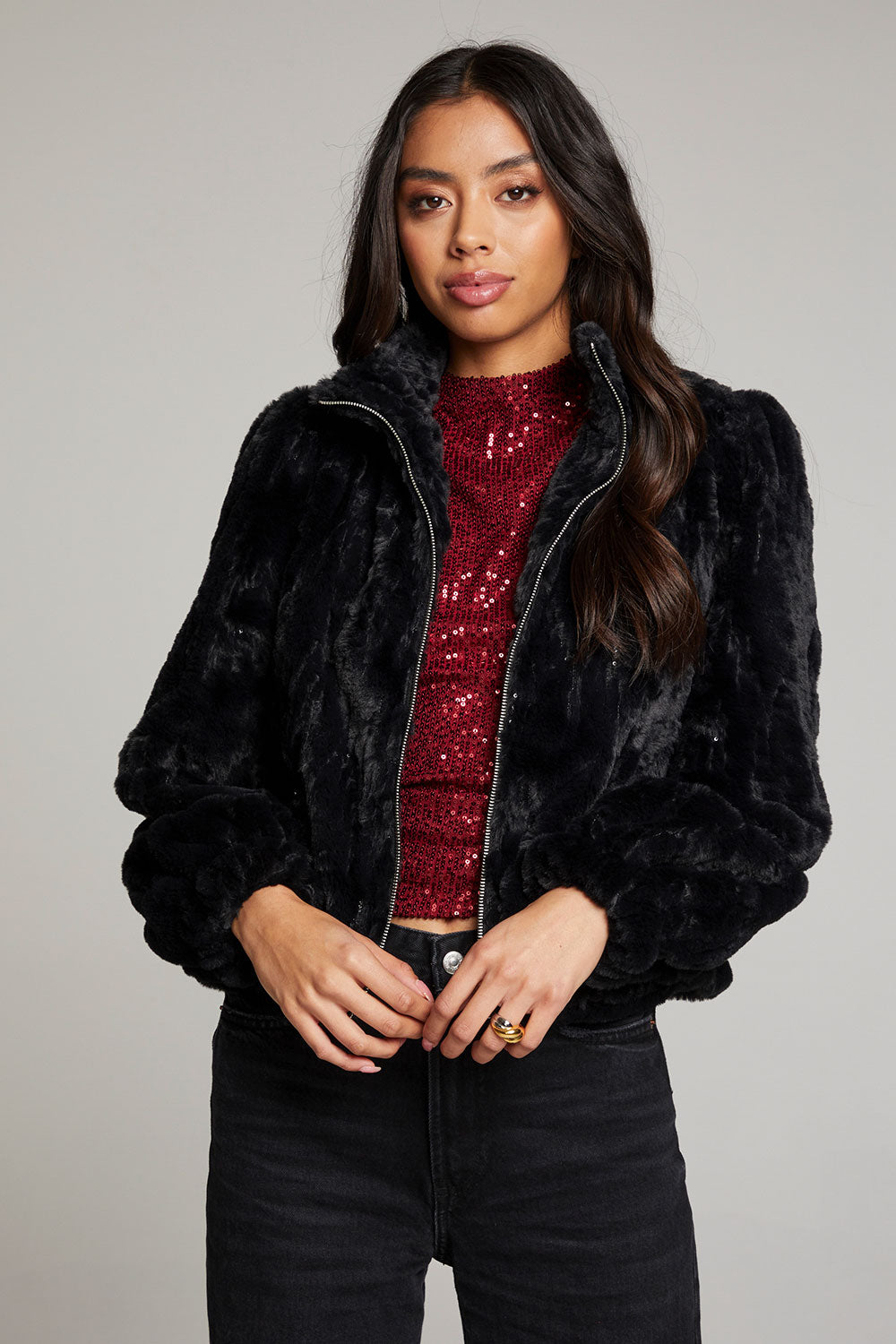 Front view of woman wearing Chaser’s Puff Sleeve Licorice Jacket over a red sequin top, paired with black pants on a plain background