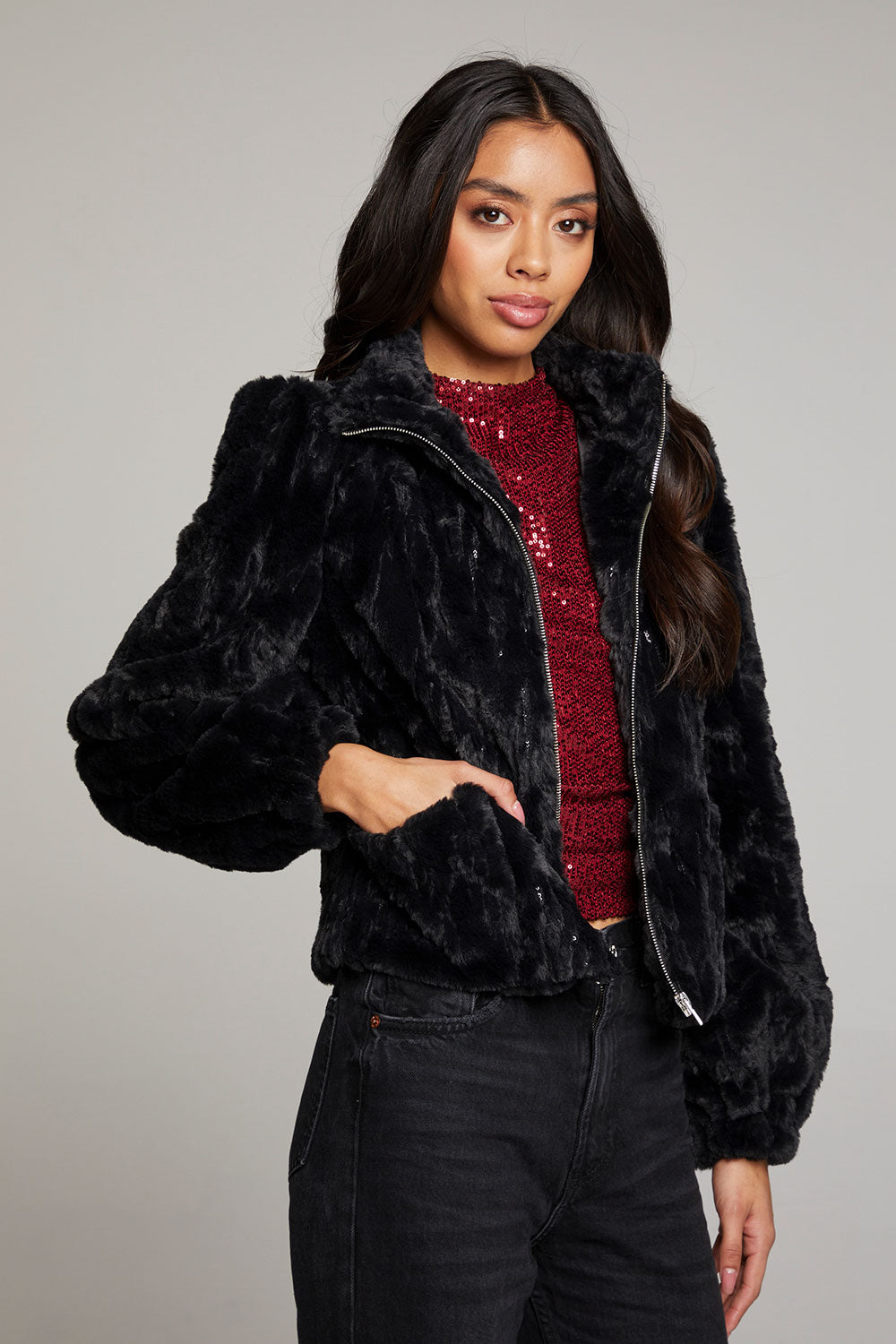 Side view of woman wearing Chaser’s Puff Sleeve Licorice Jacket with subtle puff sleeve detail over a red sequin top on a plain background