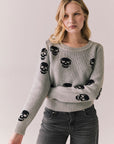 Front view of Tossed Skulls Long Sleeve sweater in Heather Grey with allover black skull motif and fitted silhouette against a plain background