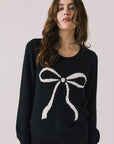 Front view of woman wearing Chaser’s true black Bow Long Sleeve with a white bow design on a plain background.