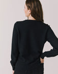 Back view of woman wearing Chaser’s true black Bow Long Sleeve on a plain background.