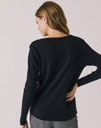 Back view of woman wearing Chaser's black Apres Ski Milano Military Thermal Long Sleeve Tee on a plain background