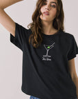 Front view of woman wearing Chaser’s black Tini Time Tee with martini glass graphic and “Tini Time” text on a plain background