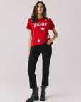 Full body view of woman wearing Chaser’s Rouge Red David Bowie Ziggy Stardust Tee with black jeans and black boots on a light gray background (Licensed band collaboration — features official David Bowie branding for SEO relevance)