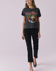 Full body view of woman wearing Chaser’s Willie Nelson Willie Christmas Tee with colorful graphic design and blue jeans on a plain background (licensed band collaboration)
