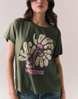 Front view of model wearing Woodstock Festival Flower Tee in bronze green with cream and pink floral graphic and vintage font against a plain background