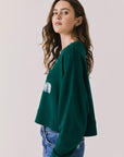 Side view of woman wearing Chaser’s Blue Grass Green C’est Le Weekend Long Sleeve with relaxed fit on a plain background