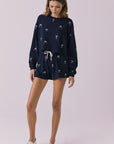 Full body view of woman wearing Chaser’s navy Tossed Bows Shorts with matching Tossed Bows Long Sleeve top on a white background