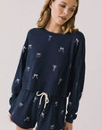 Front view of woman wearing Chaser’s navy Tossed Bows Long Sleeve with small bow prints on a white background