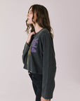 Side view of woman wearing Chaser's black oversized Black Sabbath Vol 4 Long Sleeve top with a graphic design, black pants on a white background
