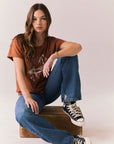Full body shot of model sitting in Wild Horses tee and denim.
