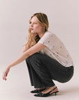 Full side view of Tossed Bolts short sleeve tee in white with scattered black lightning bolt graphic and relaxed fit wth dark denim jeans against a plain background