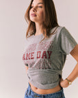 Gray short sleeve tee with maroon graphic text and relaxed fit.