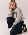Full body view of model crouching in St. Barth Yacht Club Pullover styled casually with jeans.