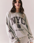 Front view of NYC Stars Pullover in Heather Grey with bold chest lettering and black star sleeves against a plain background