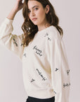 Side view of woman wearing Chaser’s Starry White French Scripts Long Sleeve with French phrases like “Merci” and “Bonjour” in black text on a white background