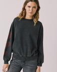 Front view of woman wearing Chaser’s Red Hearts Black Mineral Wash Long Sleeve with red hearts on the sleeves on a light pink background