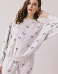 Front view of woman wearing Chaser’s light grey Tossed Hearts Long Sleeve with allover heart patterns on a white background