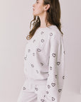 Side view of woman wearing Chaser’s light grey Tossed Hearts Long Sleeve with heart prints on a white background