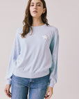 Front view of woman wearing Chaser’s Light Blue Love Stars Stitches Pullover Long Sleeve with star designs on a plain background