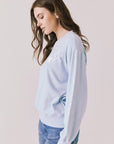 Side view of woman wearing Chaser’s Light Blue Love Stars Stitches Pullover Long Sleeve with star designs on a plain background