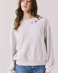 Front view of woman wearing Chaser’s Star Chainstitch Light Grey Long Sleeve with embroidered stars on a plain background