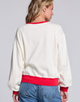 Model wearing Chaser's 'Tis the Season Pullover in Whisper White with red and green 'Tis the Season lettering and red trim, back view