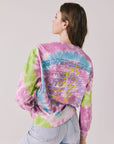 Back view of woman wearing Chaser’s Grateful Dead Rose Logo Long Sleeve with “Grateful Dead Winter 1978 West Coast Tour” text in colorful block letters on a plain background