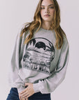 Front view of a woman wearing Chaser's gray Health Is Wealth Long Sleeve with a graphic design on a plain background