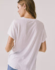 Back view of woman wearing Chaser’s The Beatles Strawberry Fields Forever White Tee on a plain background