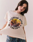Front view of model wearing the Jackson Hole Sunset Tee in white with scenic Western graphic with graphic design on a plain background