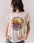 Front view of model wearing the Jackson Hole Sunset Tee in white with scenic Western graphic with graphic design on a plain background