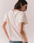 Back view of model wearing the Jackson Hole Sunset Tee in white with scenic Western graphic with graphic design on a plain background