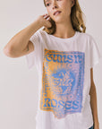 Front view of woman wearing Chaser’s white Guns N’ Roses World Tour Tee with colorful tour graphic (licensed band collaboration) on a plain background